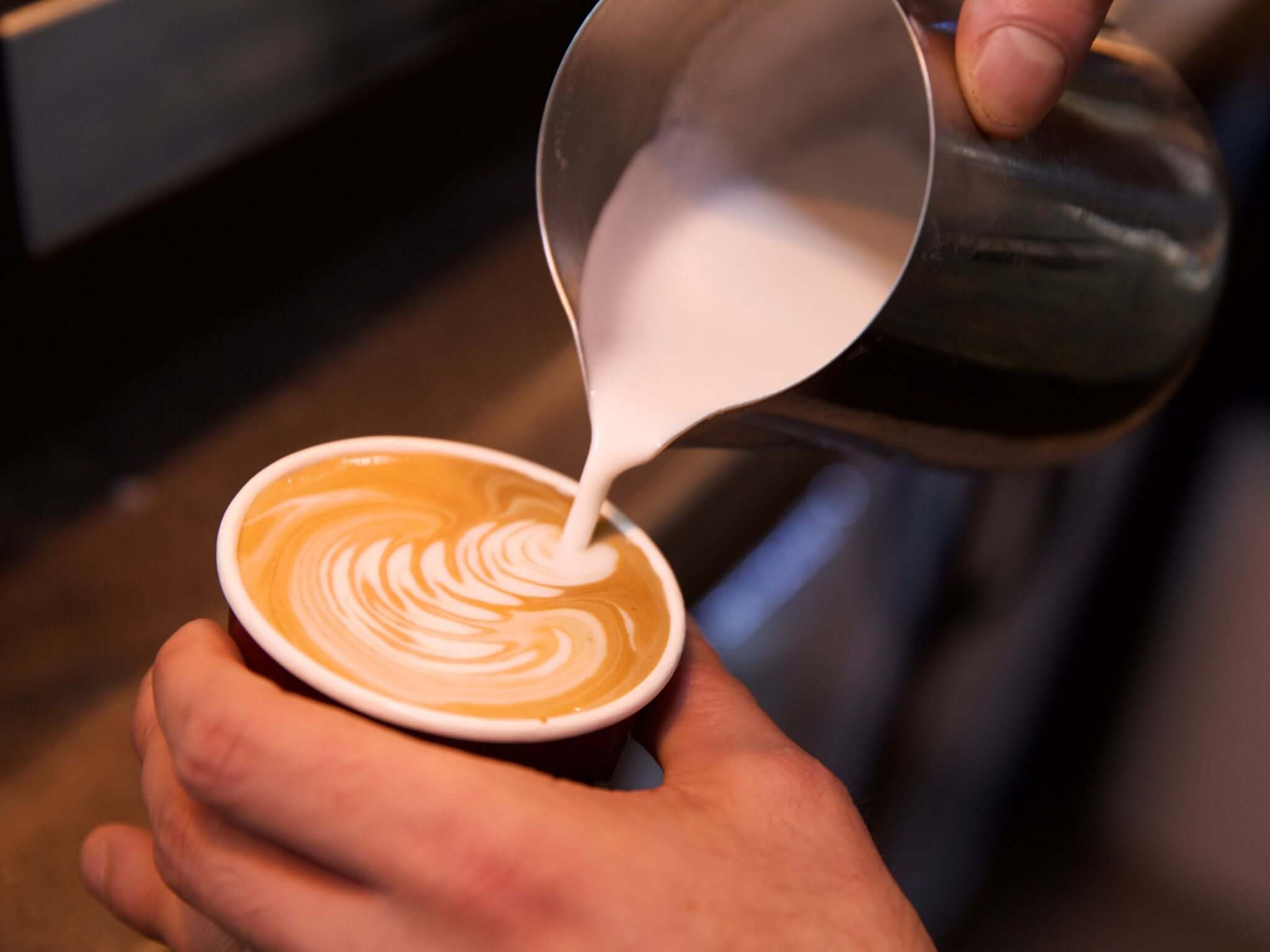 Barista pouring milk into espresso based drink