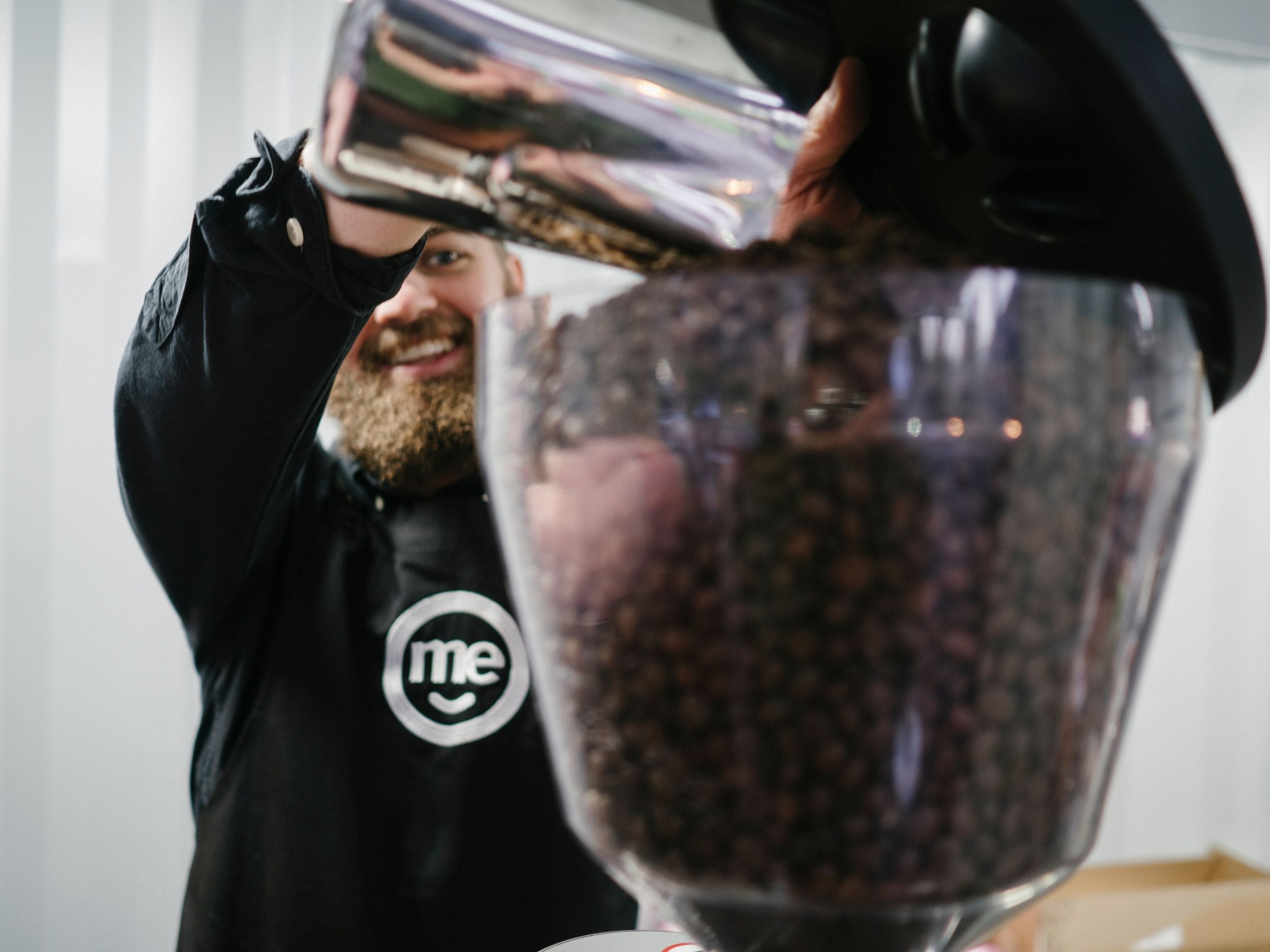 Me bank barista pouring coffee beans into hopper