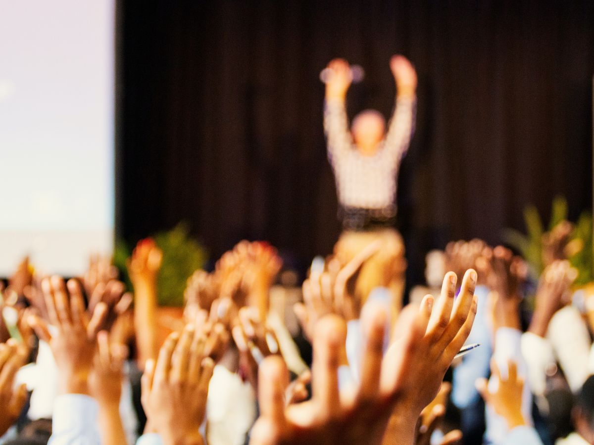 Event speaker on stand with hands raised in air