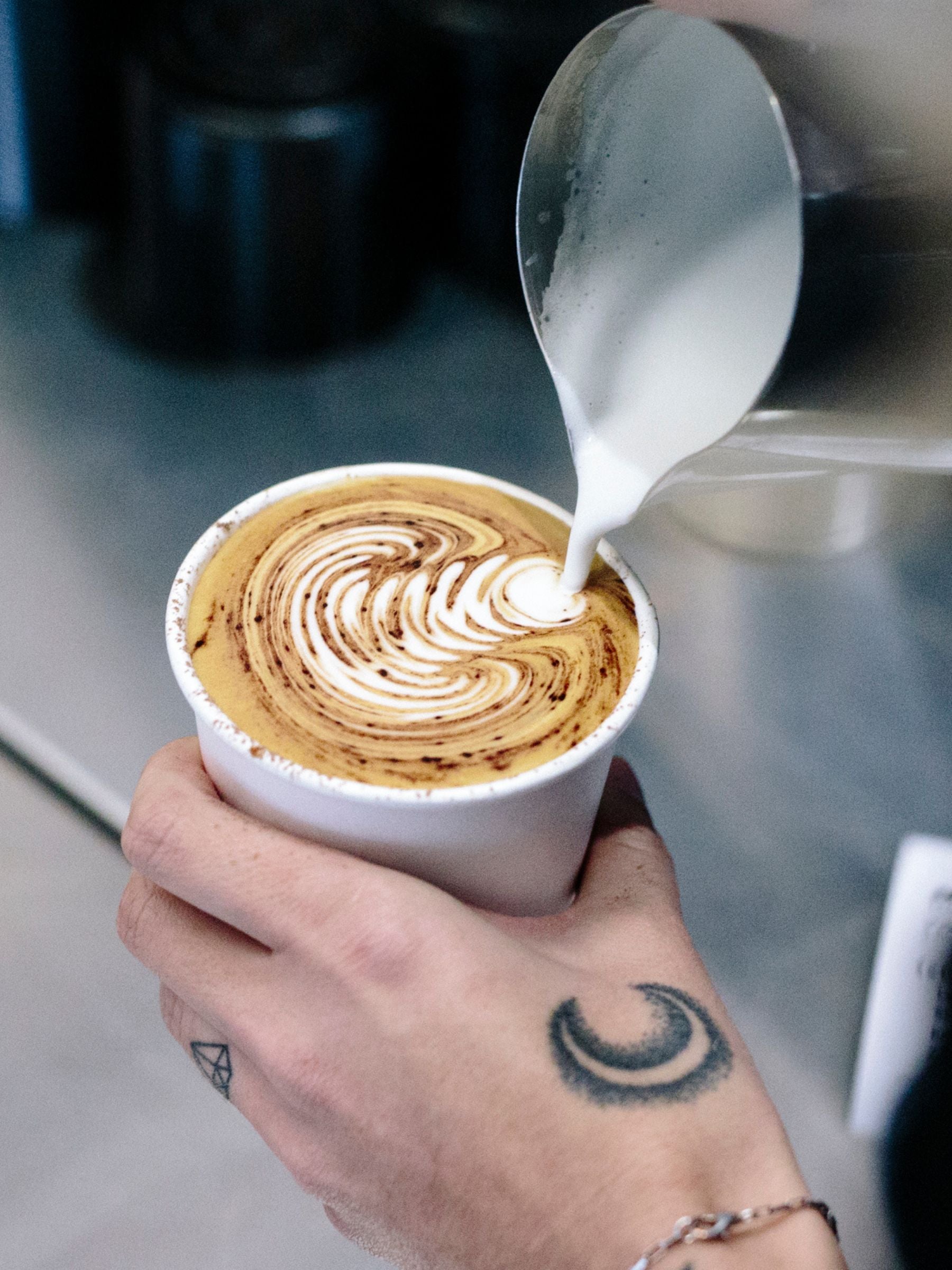 Latte art being poured into a takeaway coffee cup