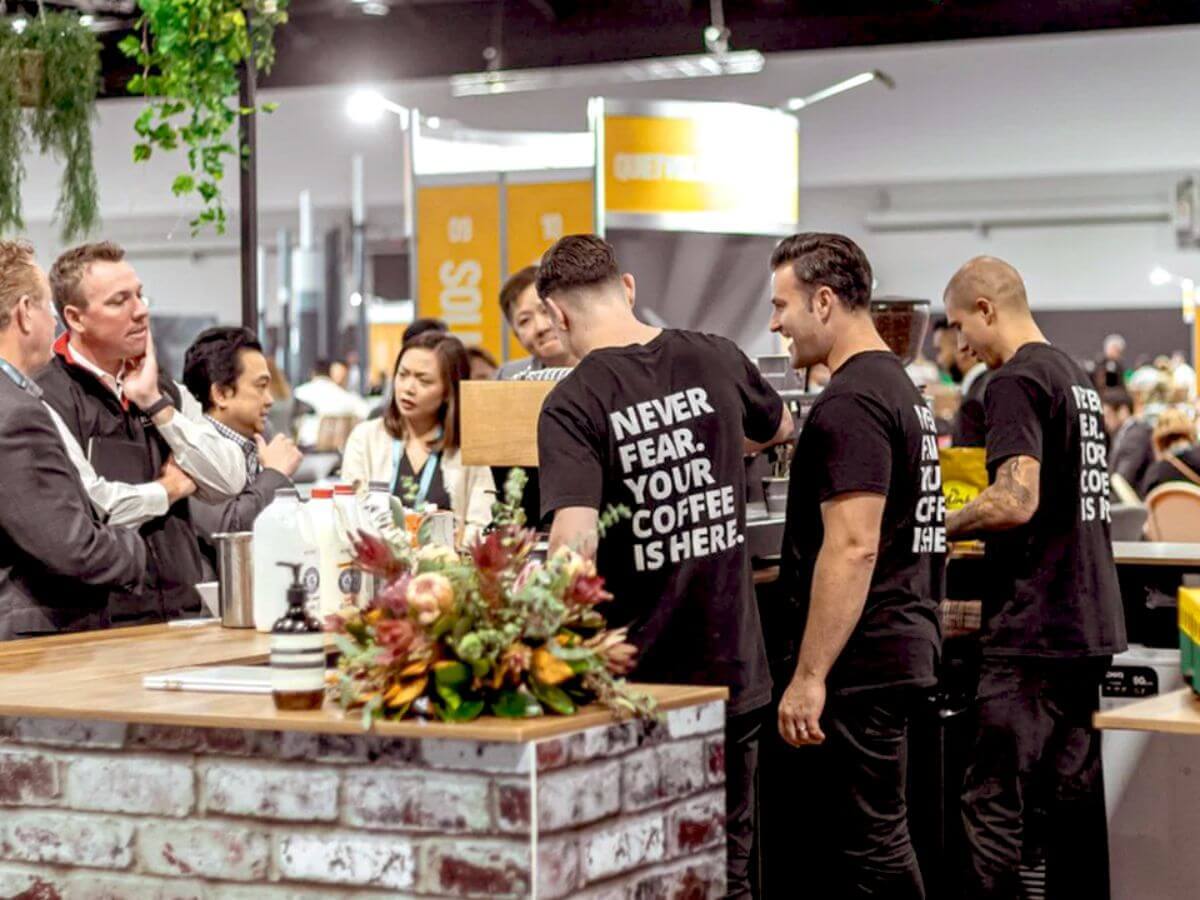 Three Coffee on Cue baristas serving trade show guests