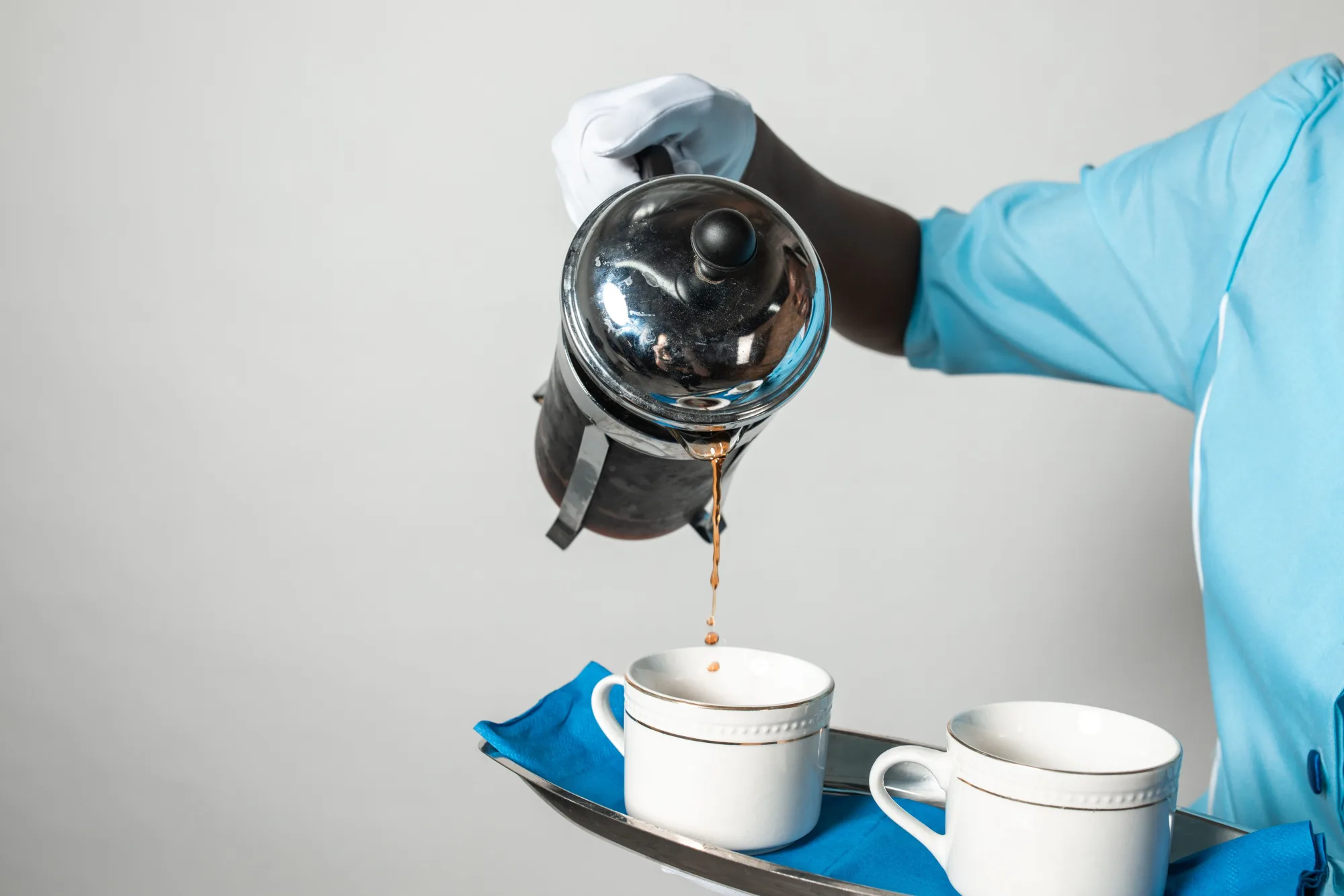 A French press pouring coffee into two cups