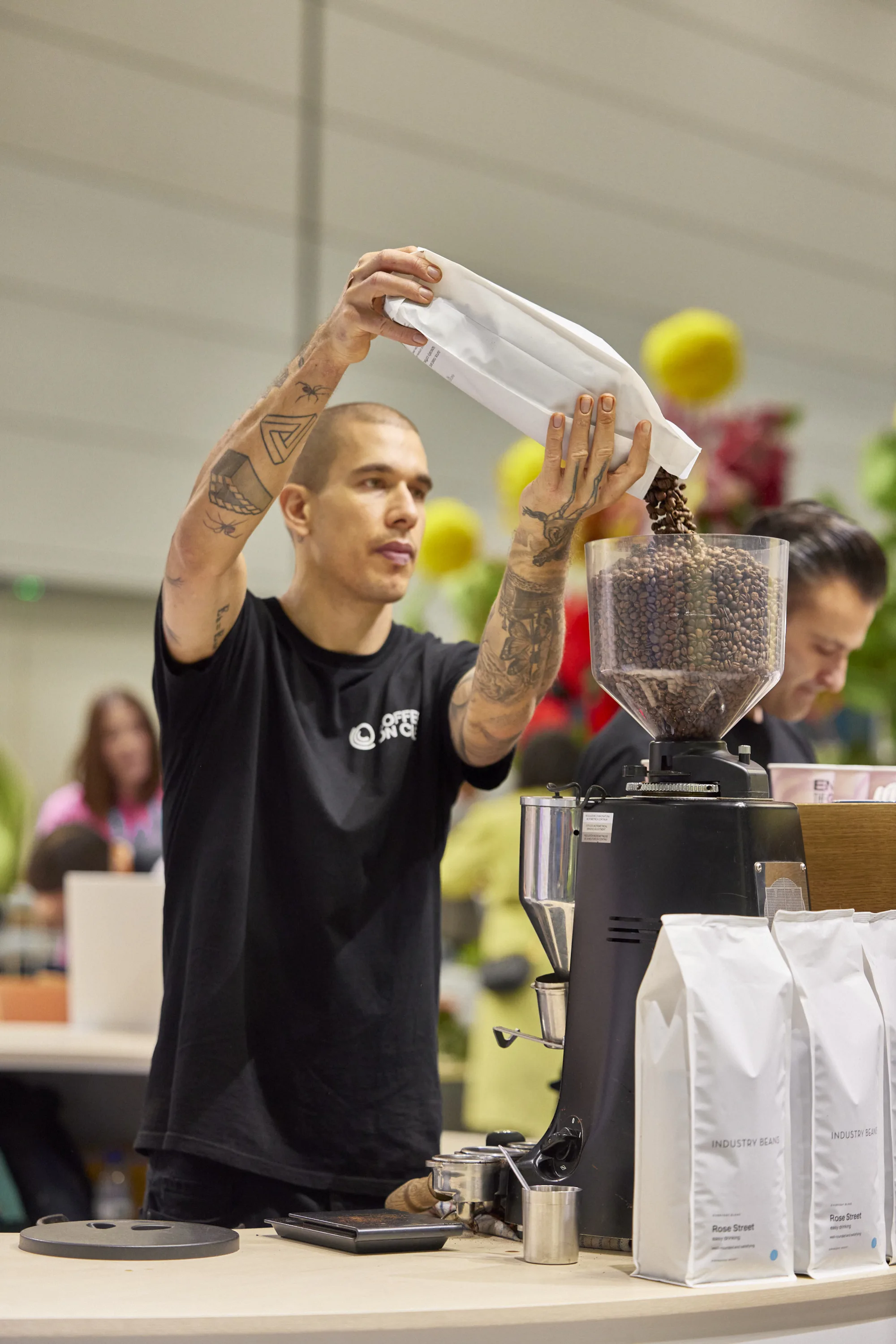 A Coffee on Cue barista filling a grinder hopper with fresh beans