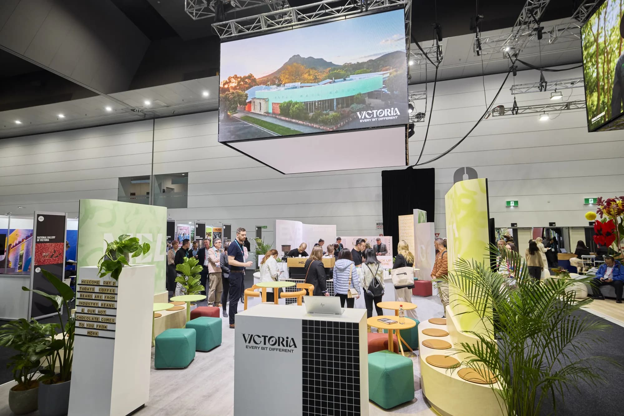 Guests queuing at a Coffee on Cue coffee bar on a busy trade-show stand, with baristas serving behind the counter