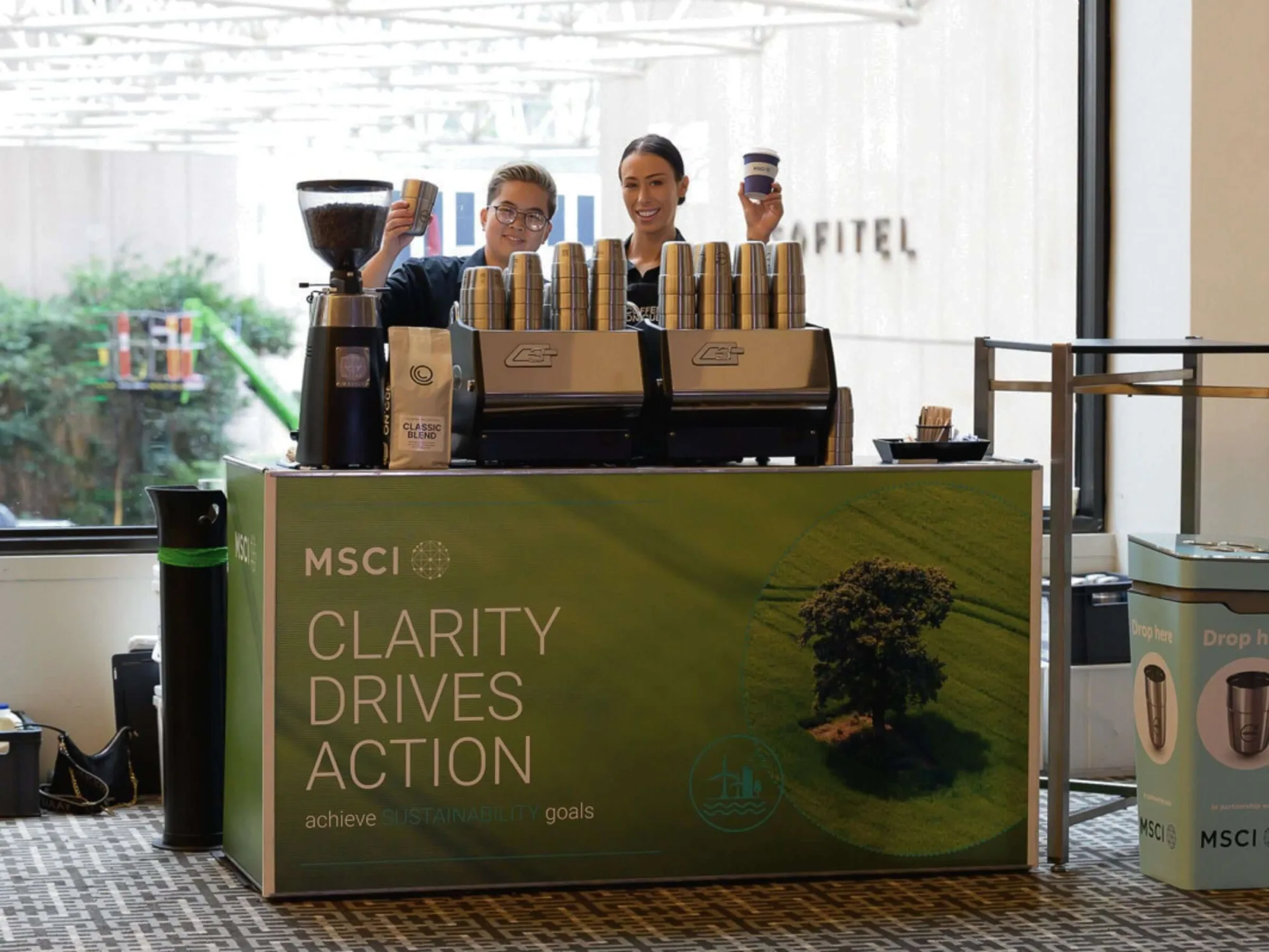 Two Coffee on Cue baristas celebrating behind the cart at a client event