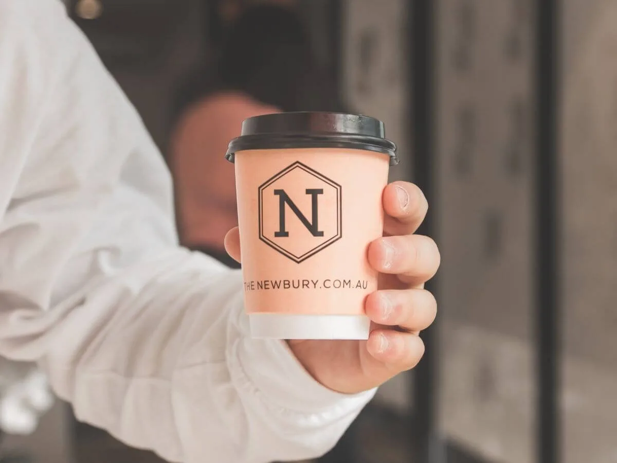 A guest holding a coffee cup printed with a client logo