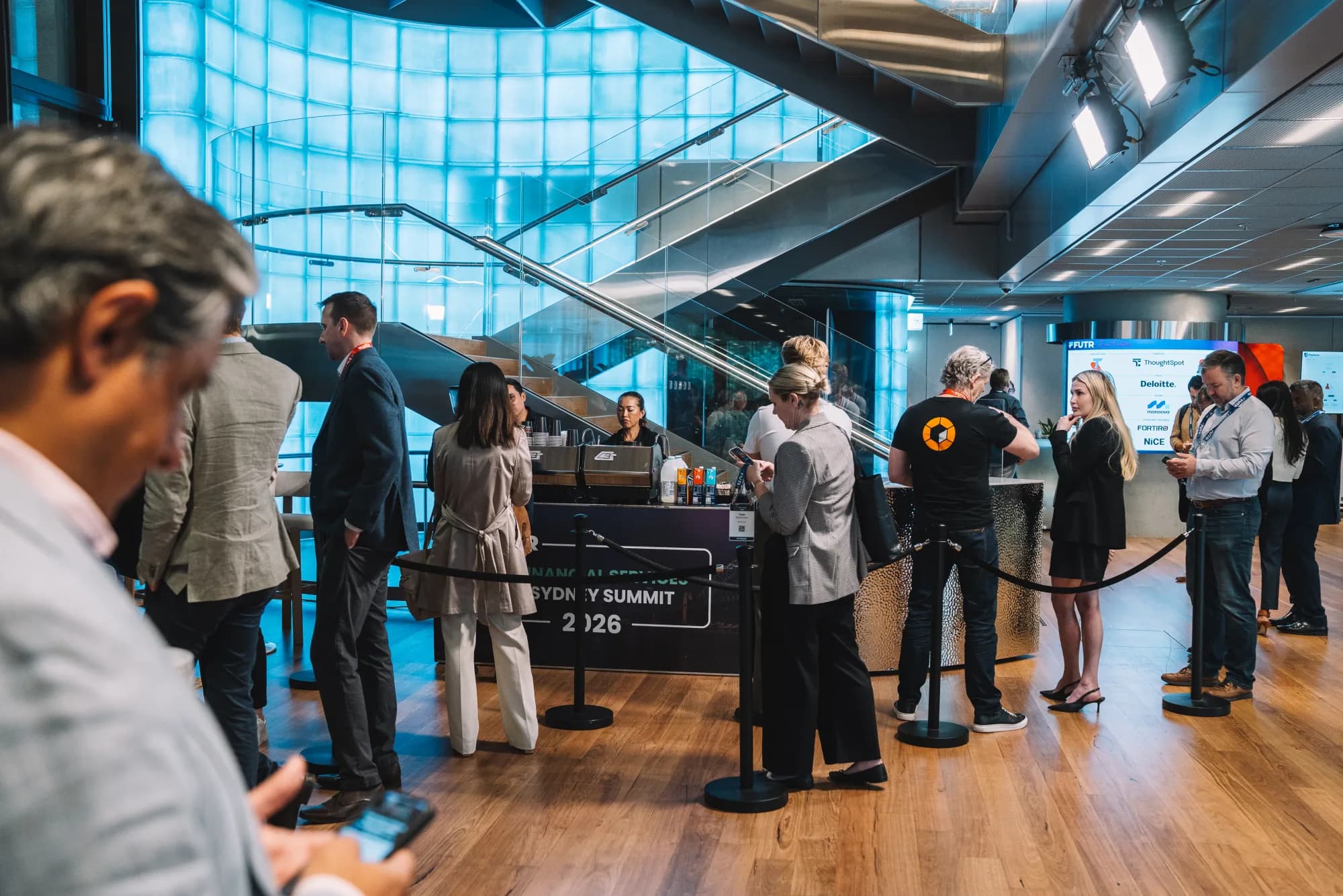 Conference delegates queueing at a Coffee on Cue cart under a glass staircase at the FUTR Financial Services Sydney Summit