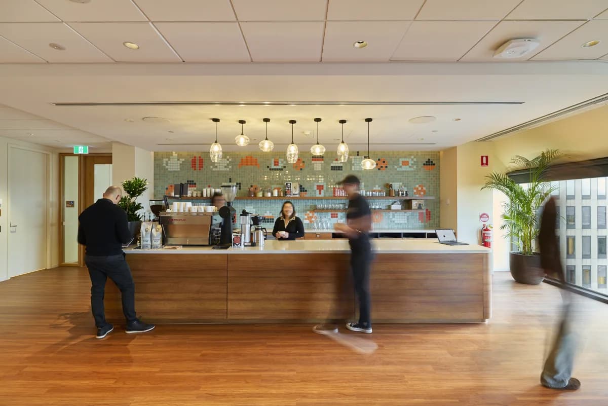 Two guests at the corporate office bar while their coffee is made