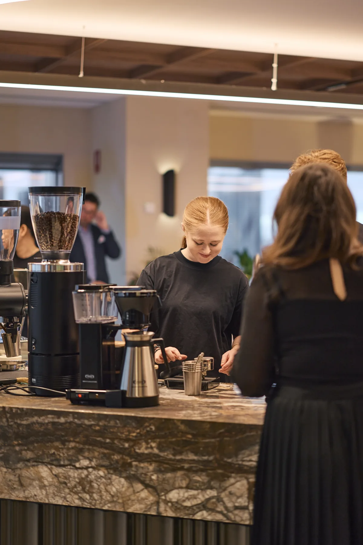 A barista at the JLL machine, making a guest their coffee