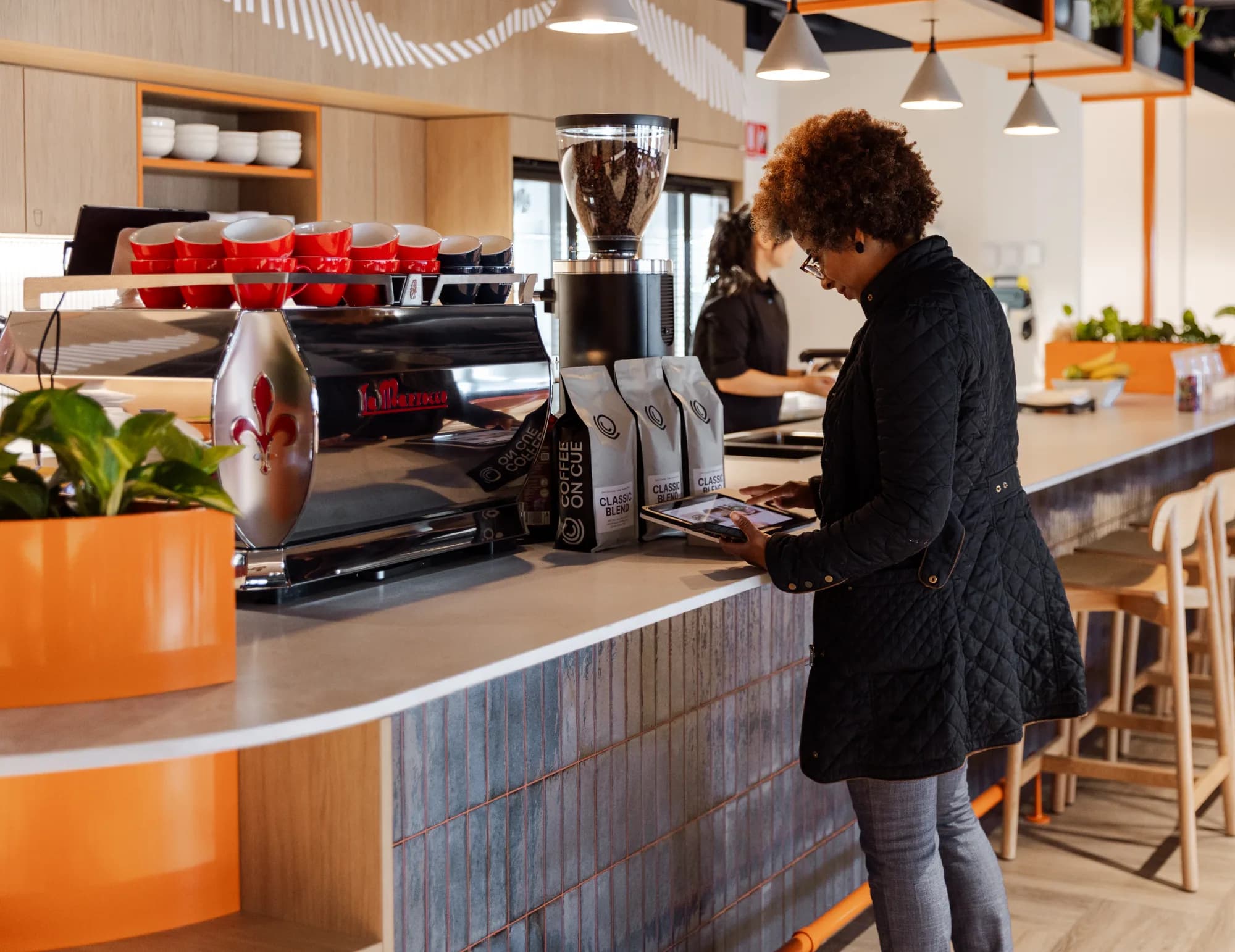 A colleague at a fully integrated custom coffee bar with a tiled front in a Sydney office