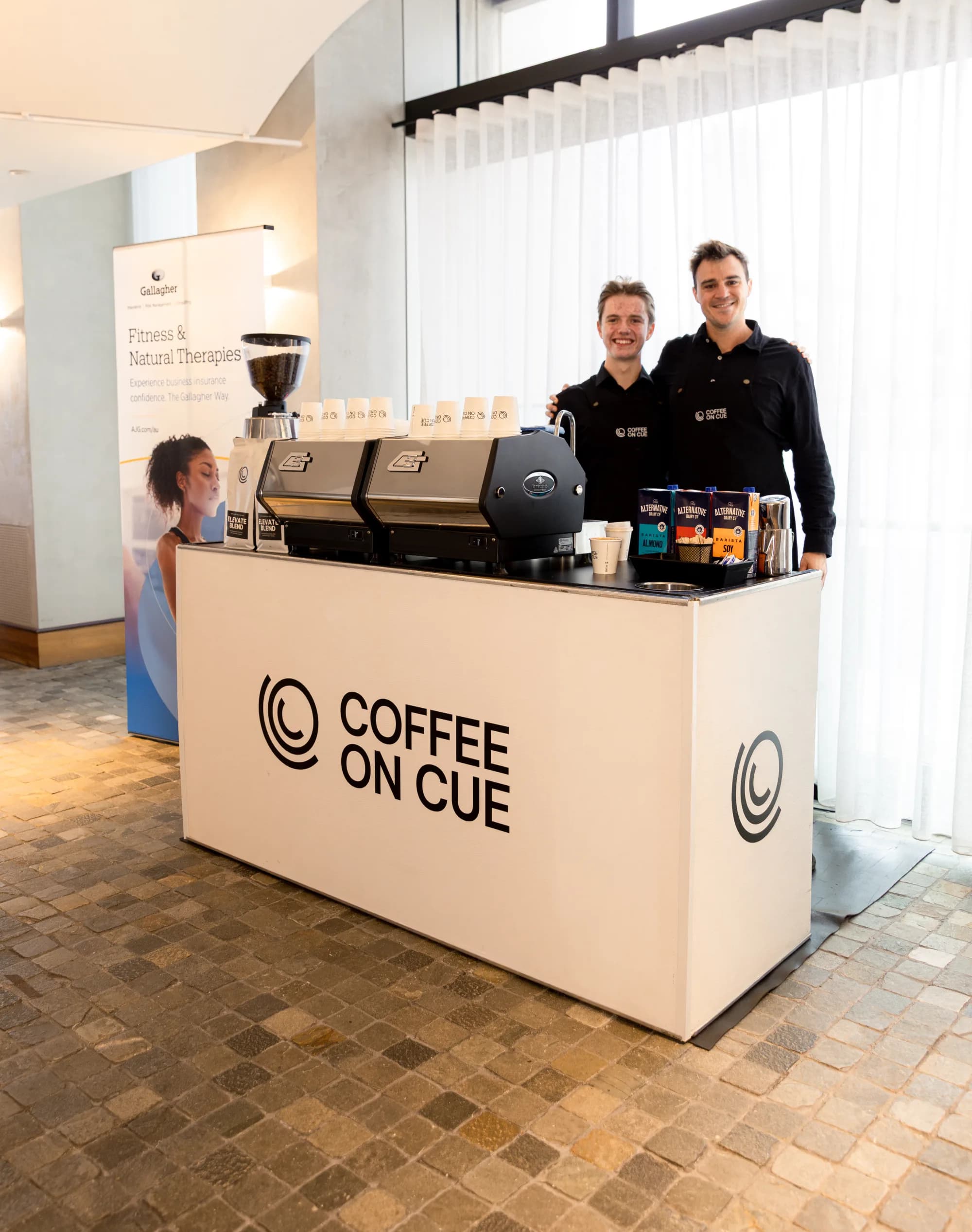 A Coffee on Cue barista working the grinder at a workplace bar