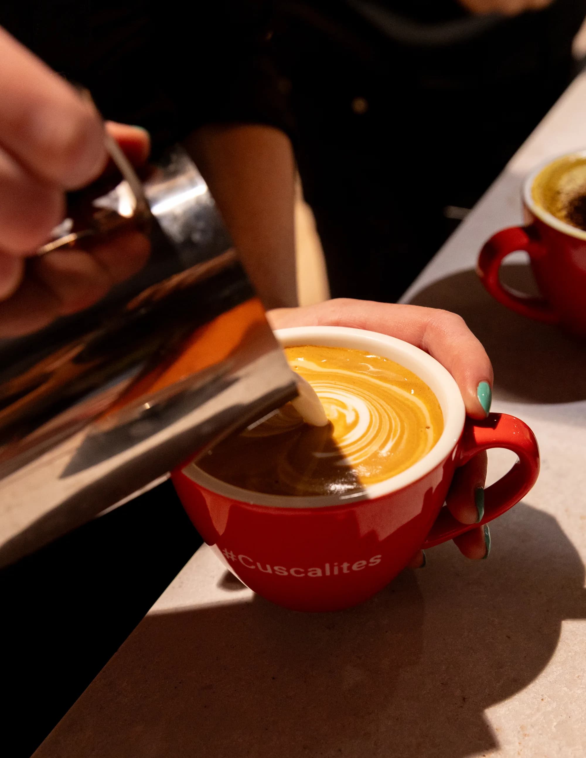 A latte art pour into a red client-branded mug, close-up