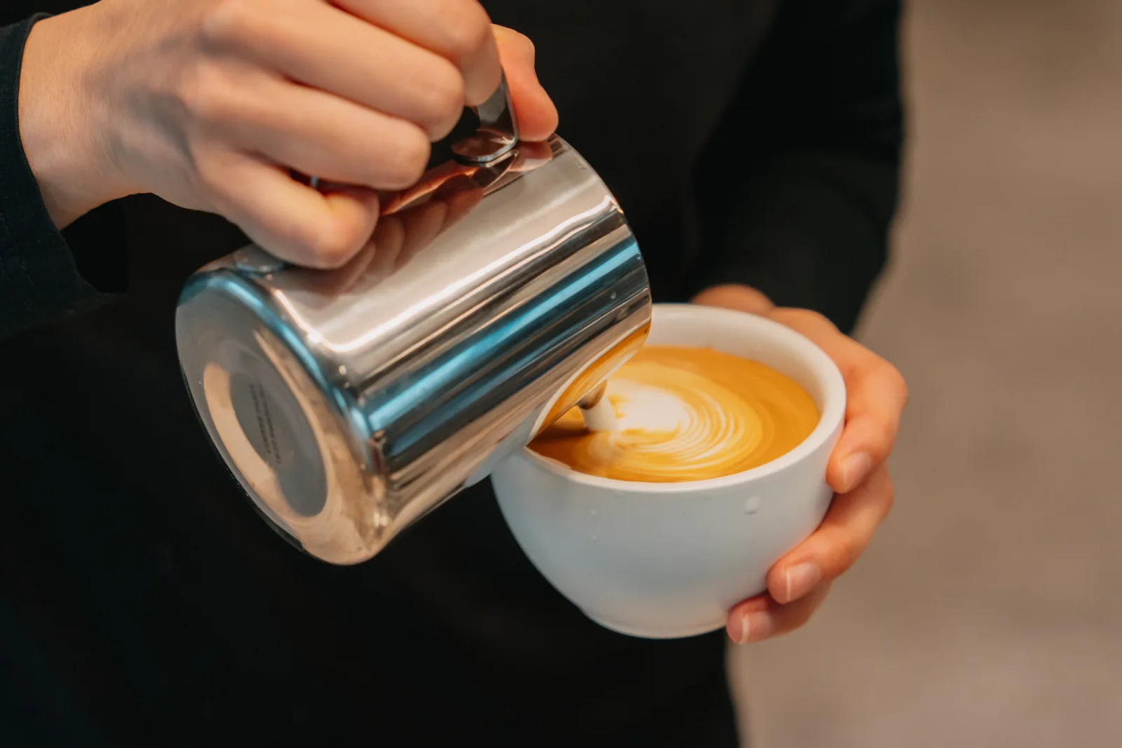 A Coffee on Cue barista pouring a rosetta into a cup