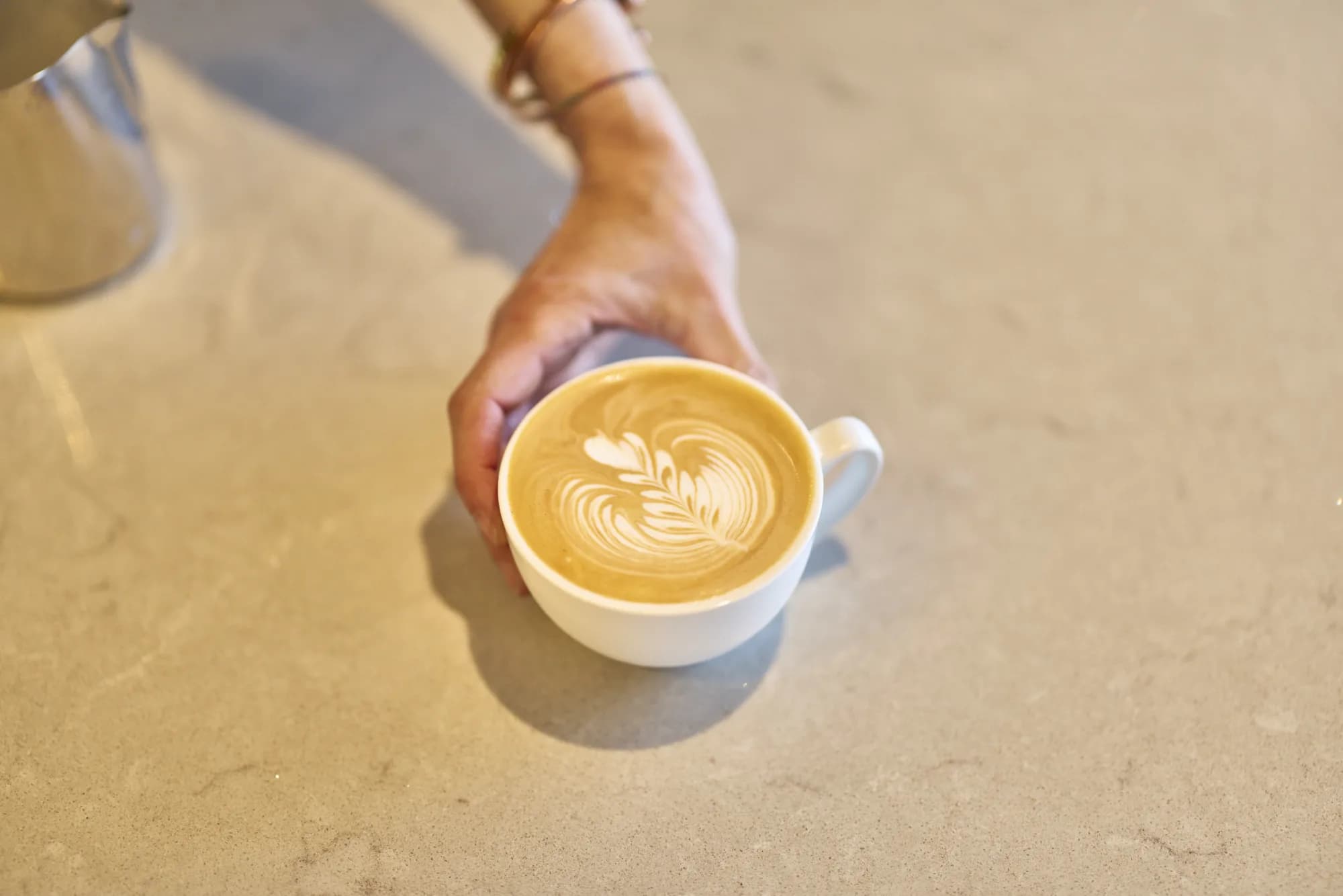 A finished latte handed across the counter at Salesforce Melbourne