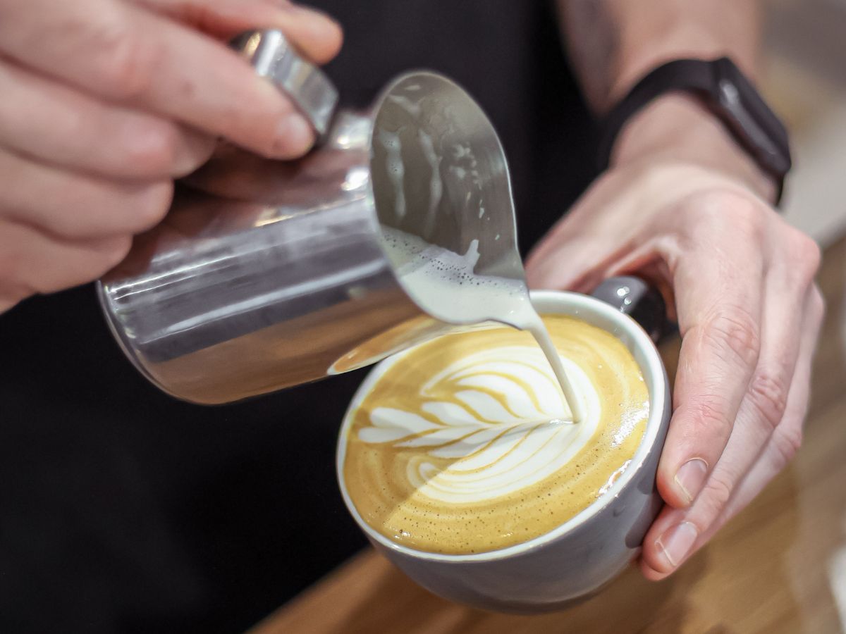 Latte art being poured into ceramic cup