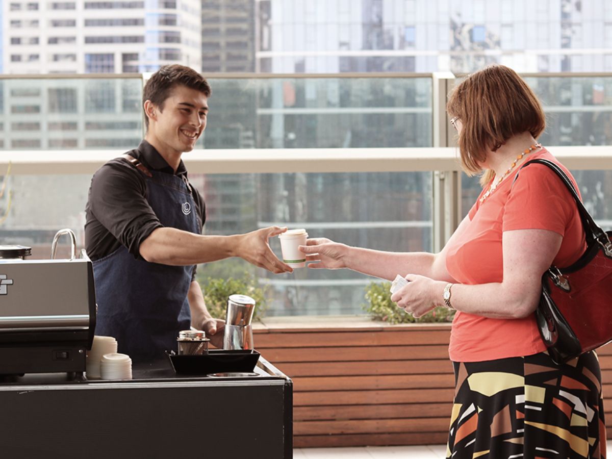 Coffee barista serving an office worker on their corporate rooftop garden area