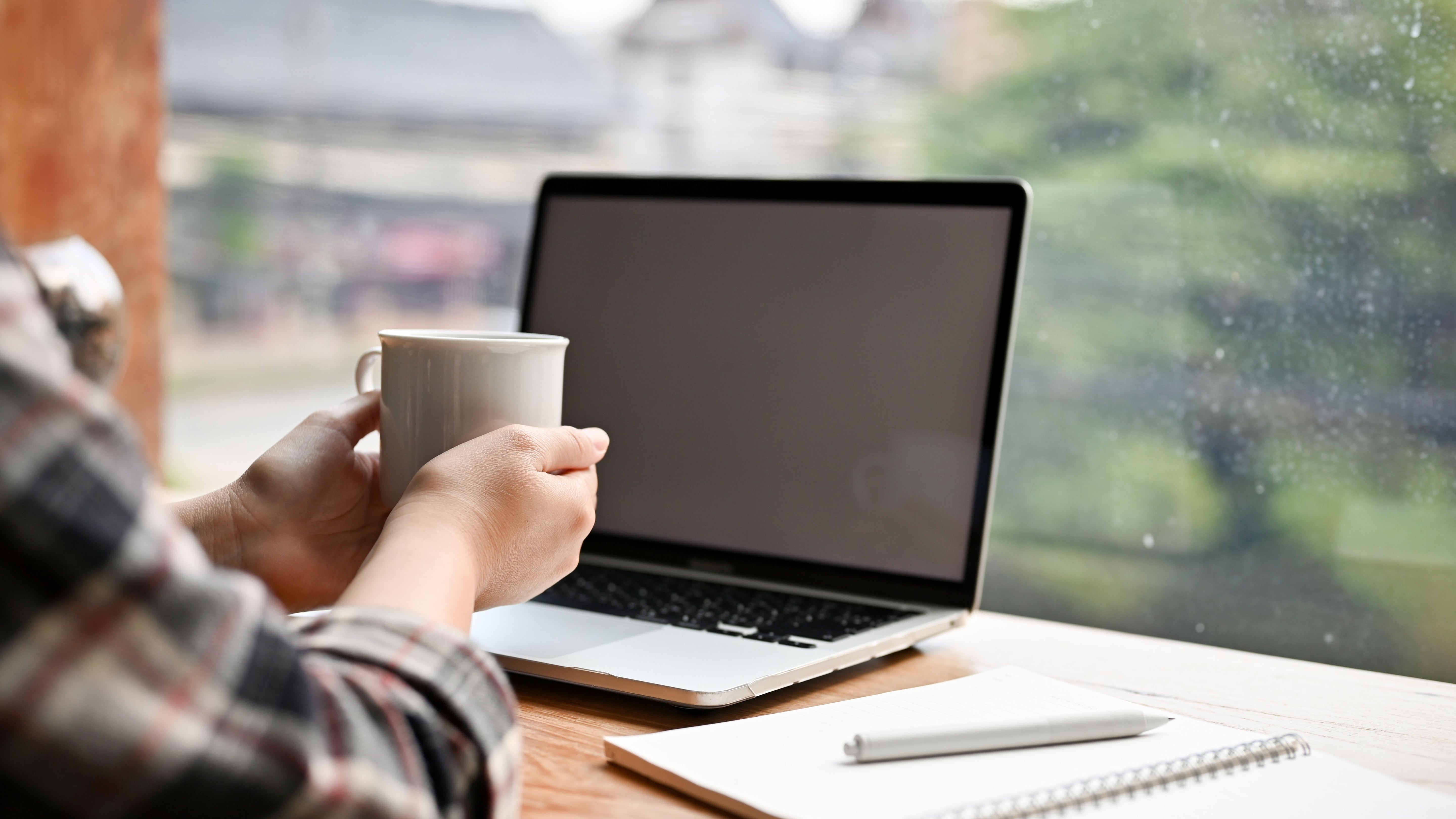 Employee with their coffee and laptop at desk