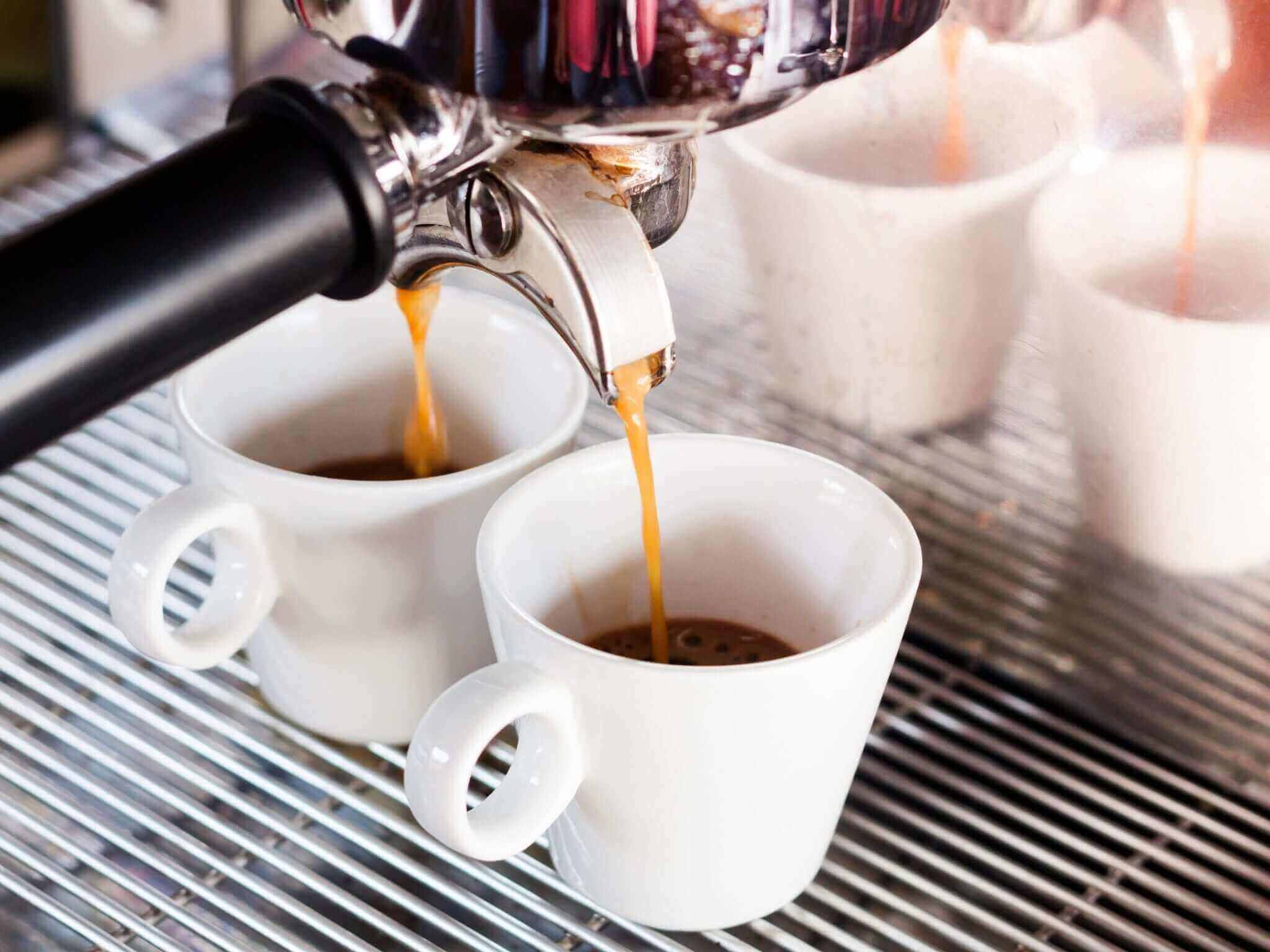 Espresso shots pouring into coffee cups
