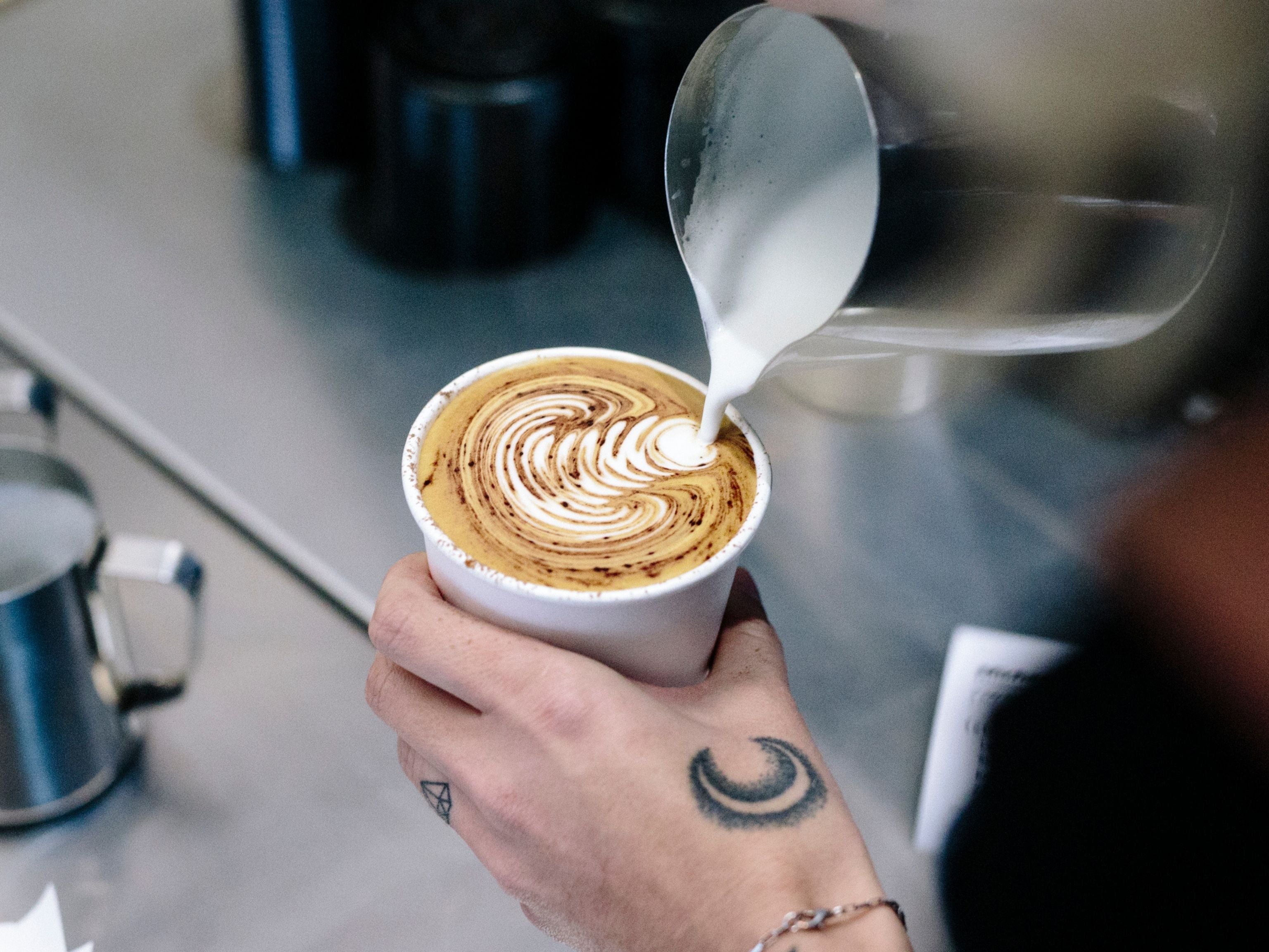 Latte art poured into takeaway coffee cup