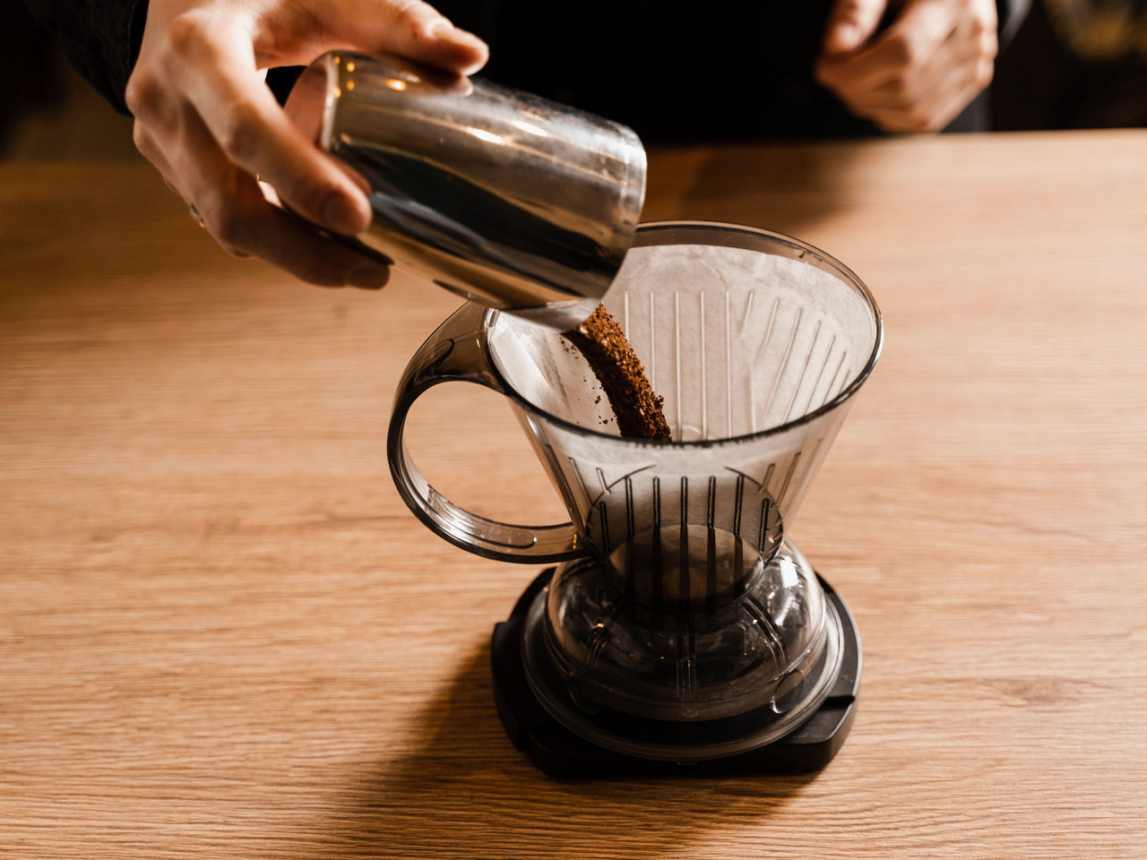 Pouring fresh coffee grounds into filter paper