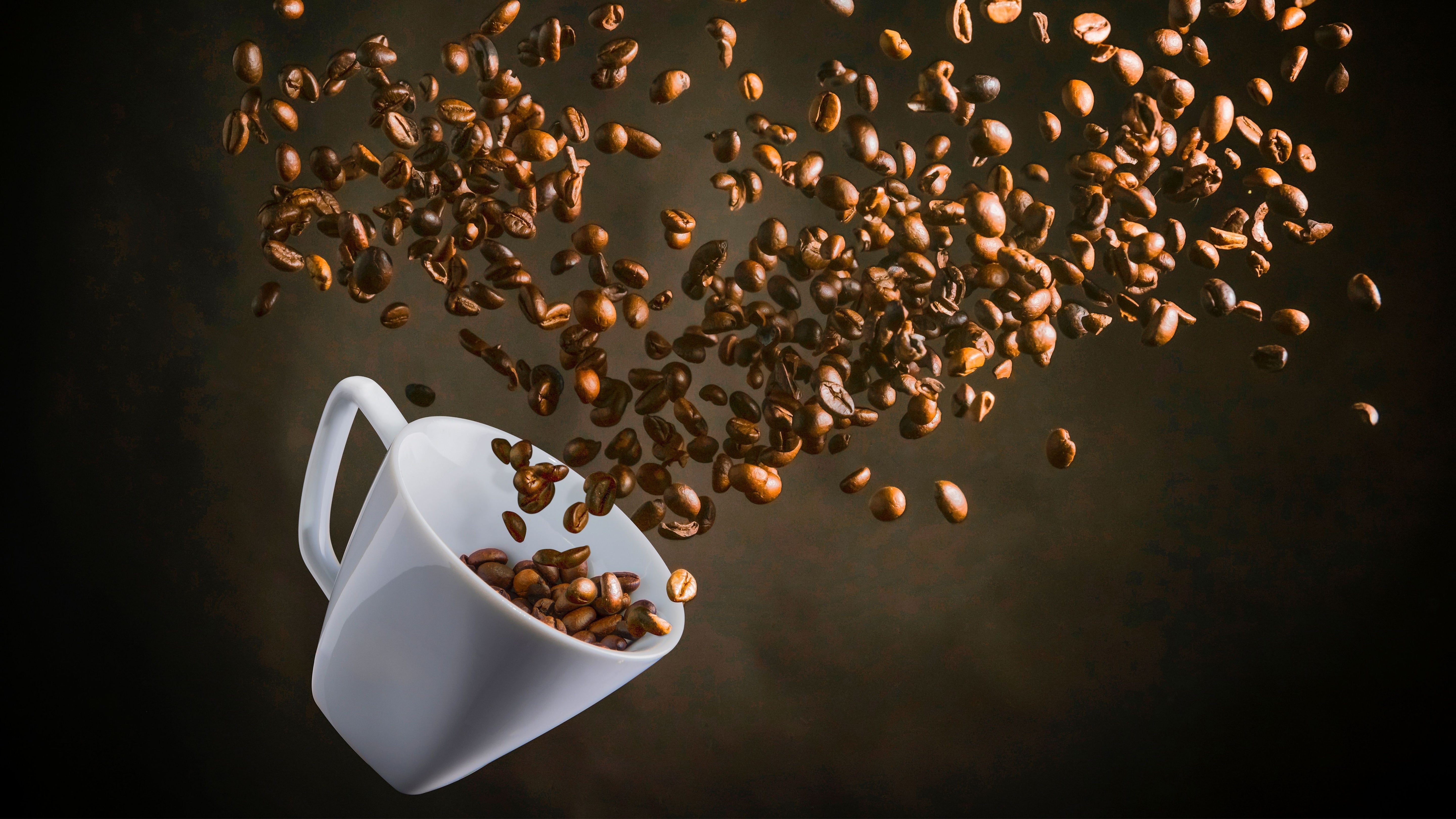 Coffee beans flying out of ceramic cup