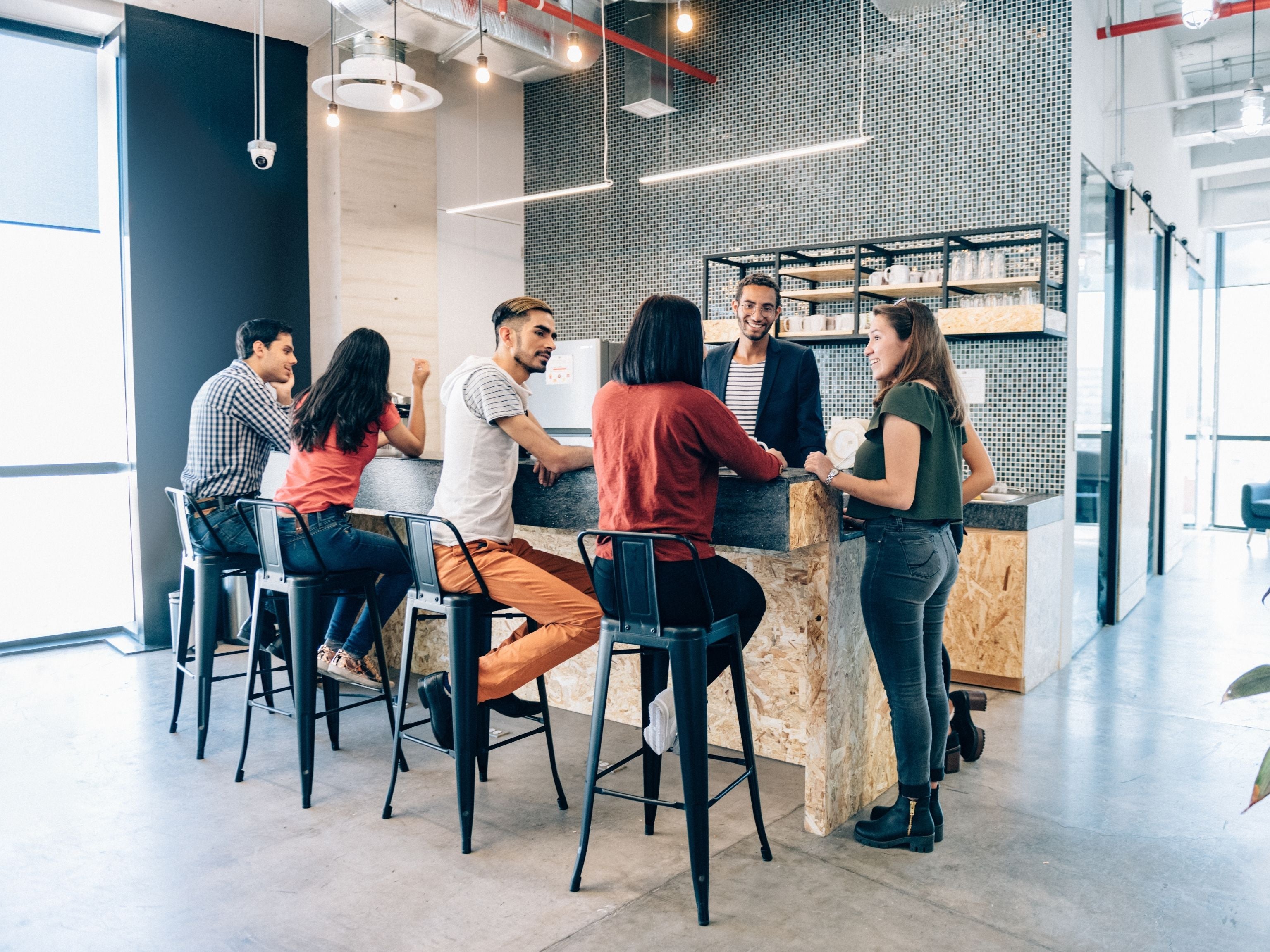 Team in the office kitchen drinking coffee together