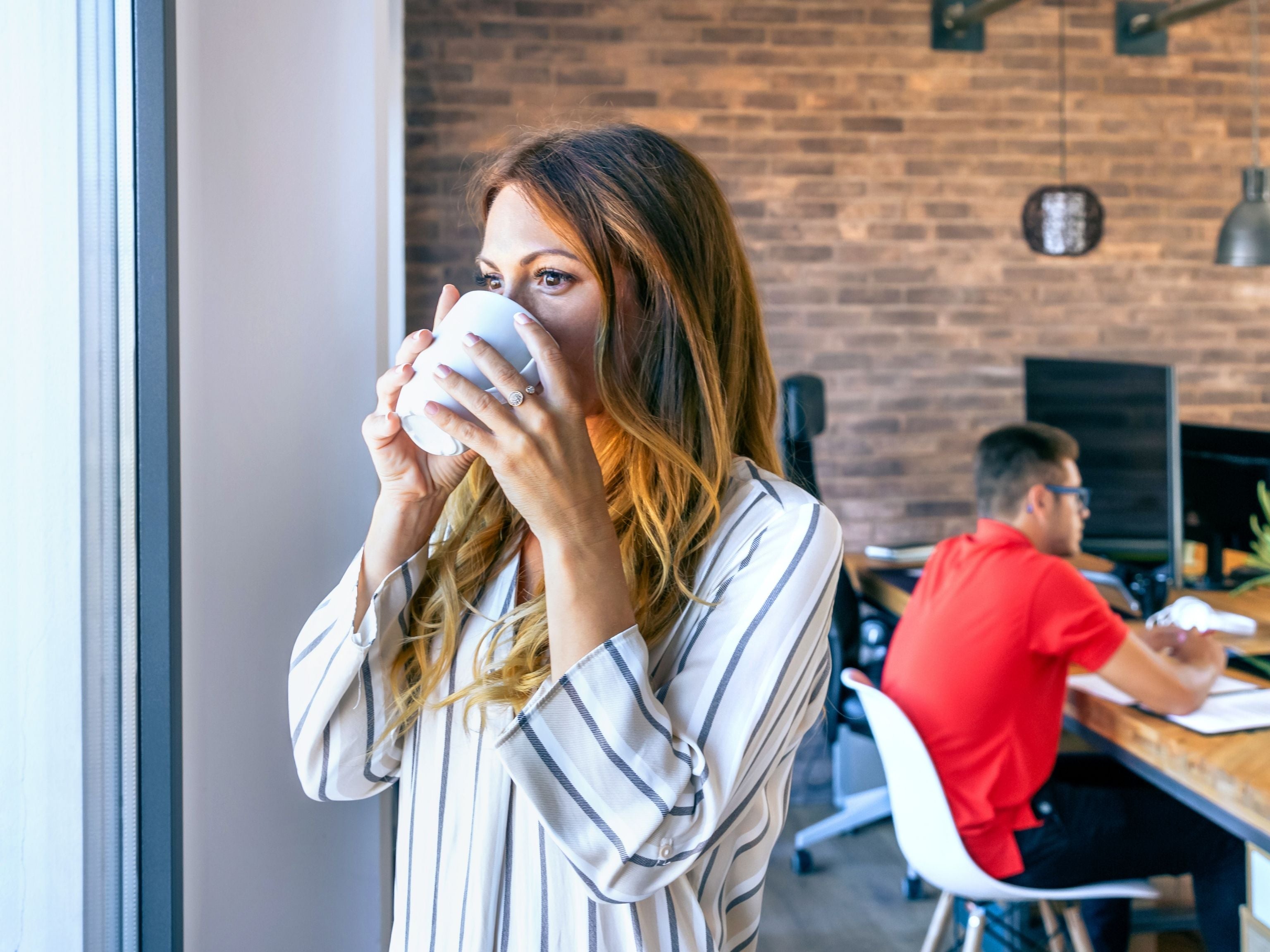 Woman drinking coffee by the window at the office
