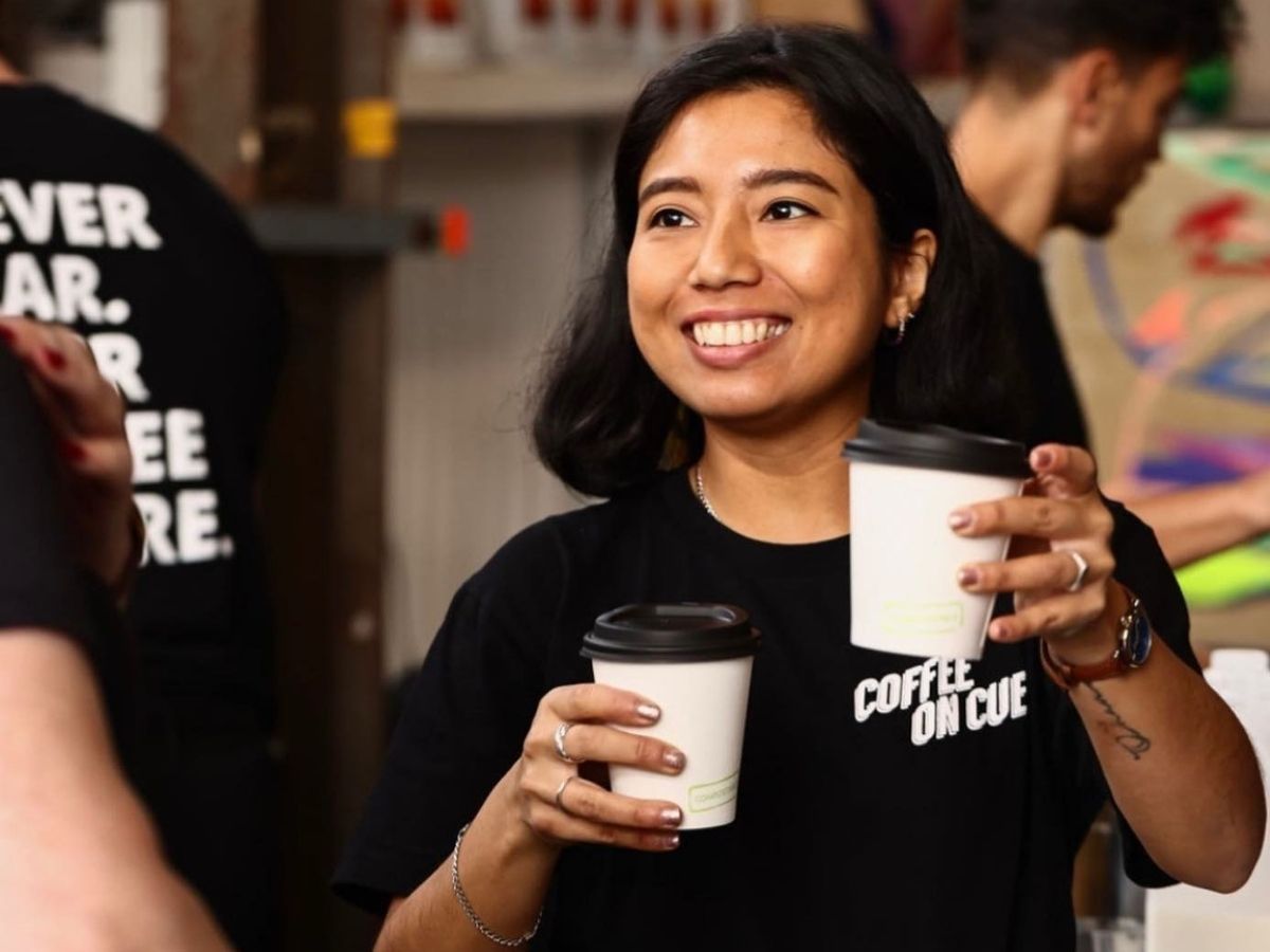 Barista handing out takeaway coffees at market