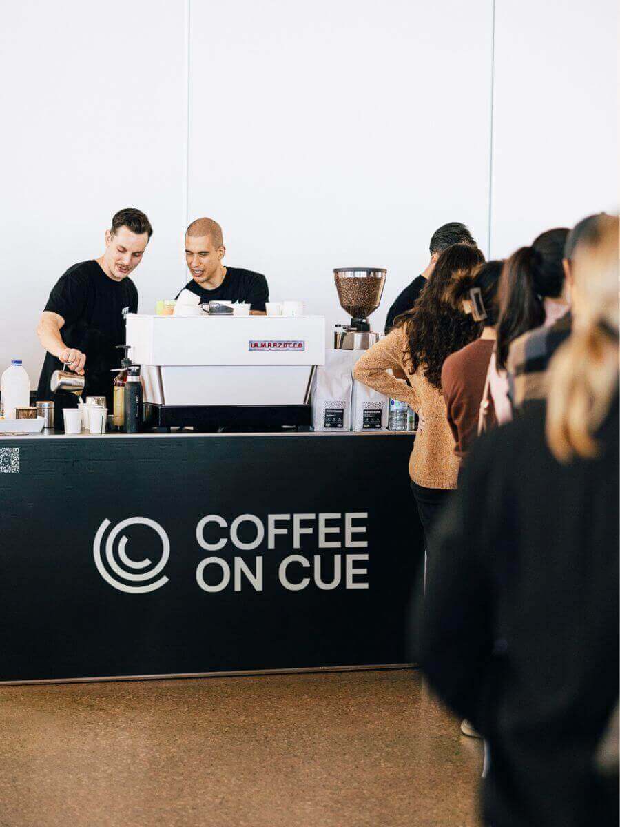 Two Coffee on Cue baristas serving guests at an event