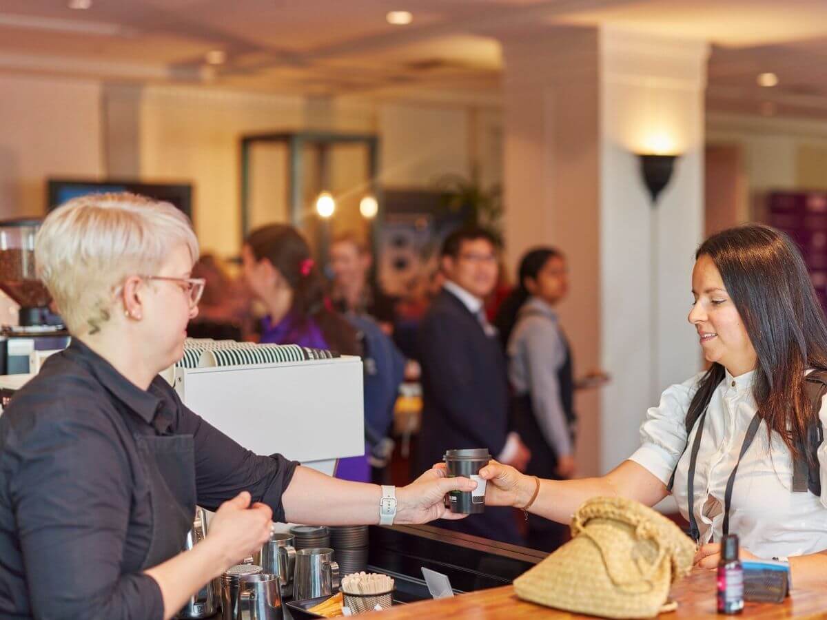 Barista passing coffee over to event guest