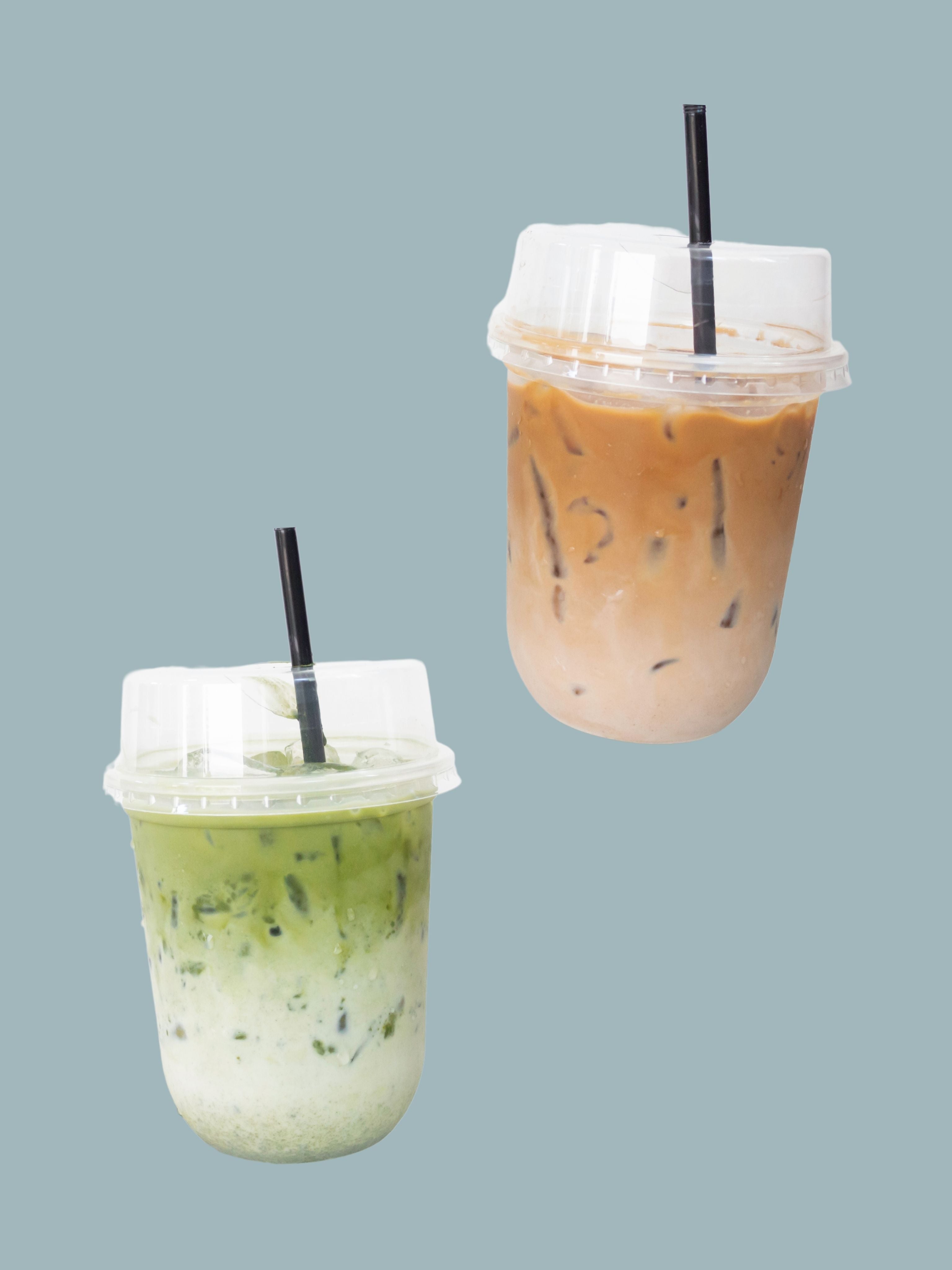 Two iced beverages in plastic cups with straws