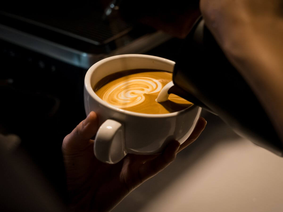 Pouring steamed milk into espresso base