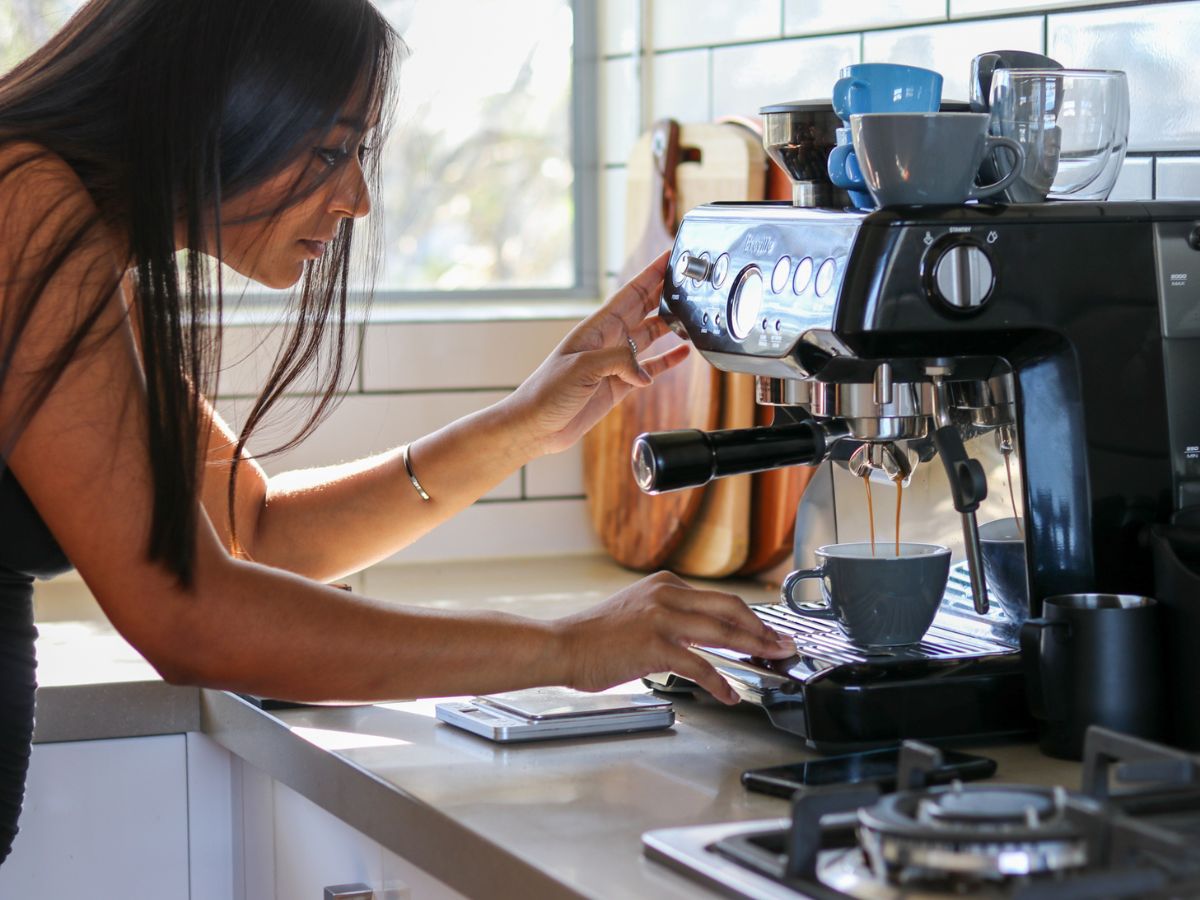Woman brewing coffee on home espresso machine