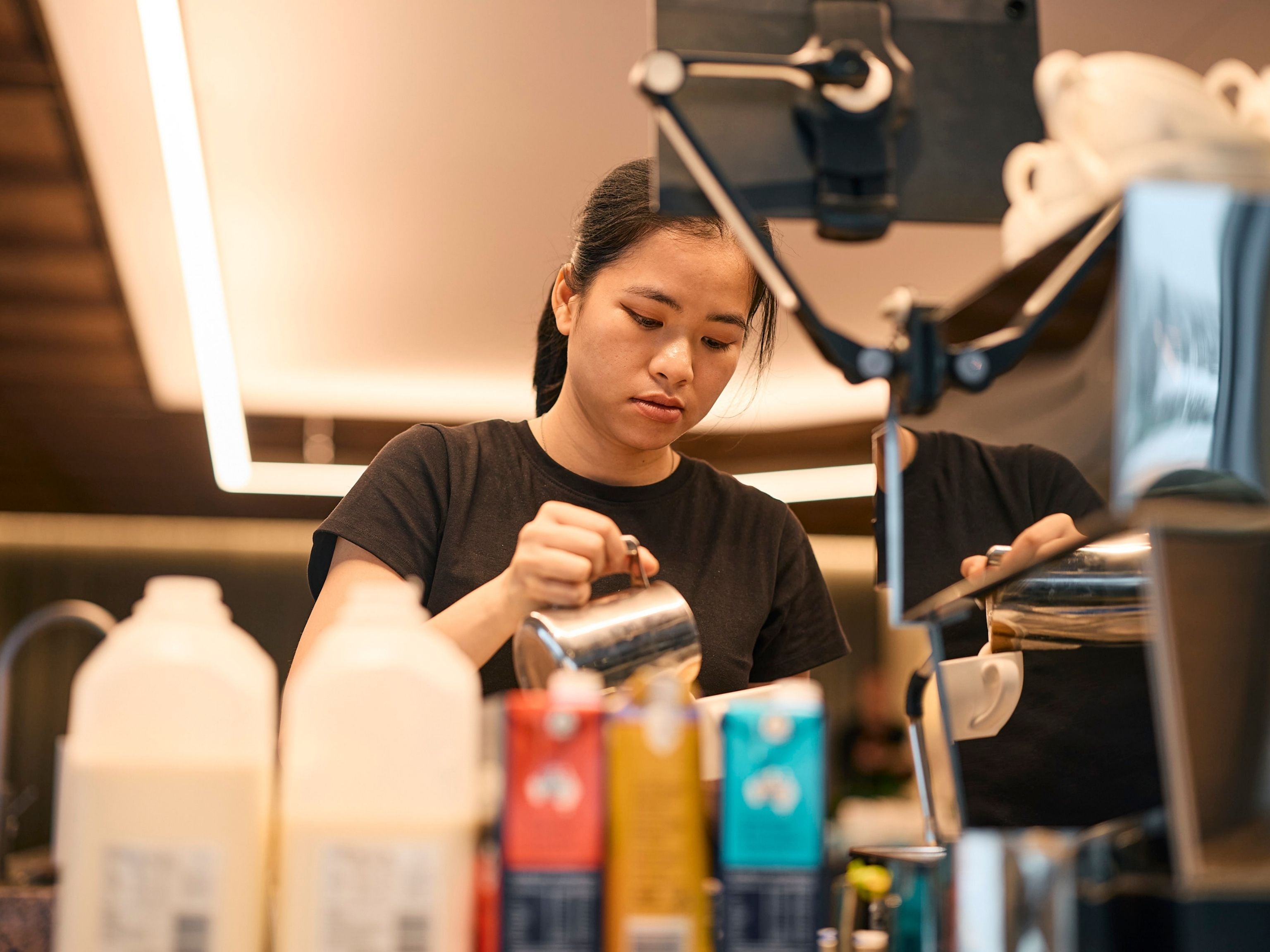 JLL barista carefully pouring steamed milk into a coffee mug