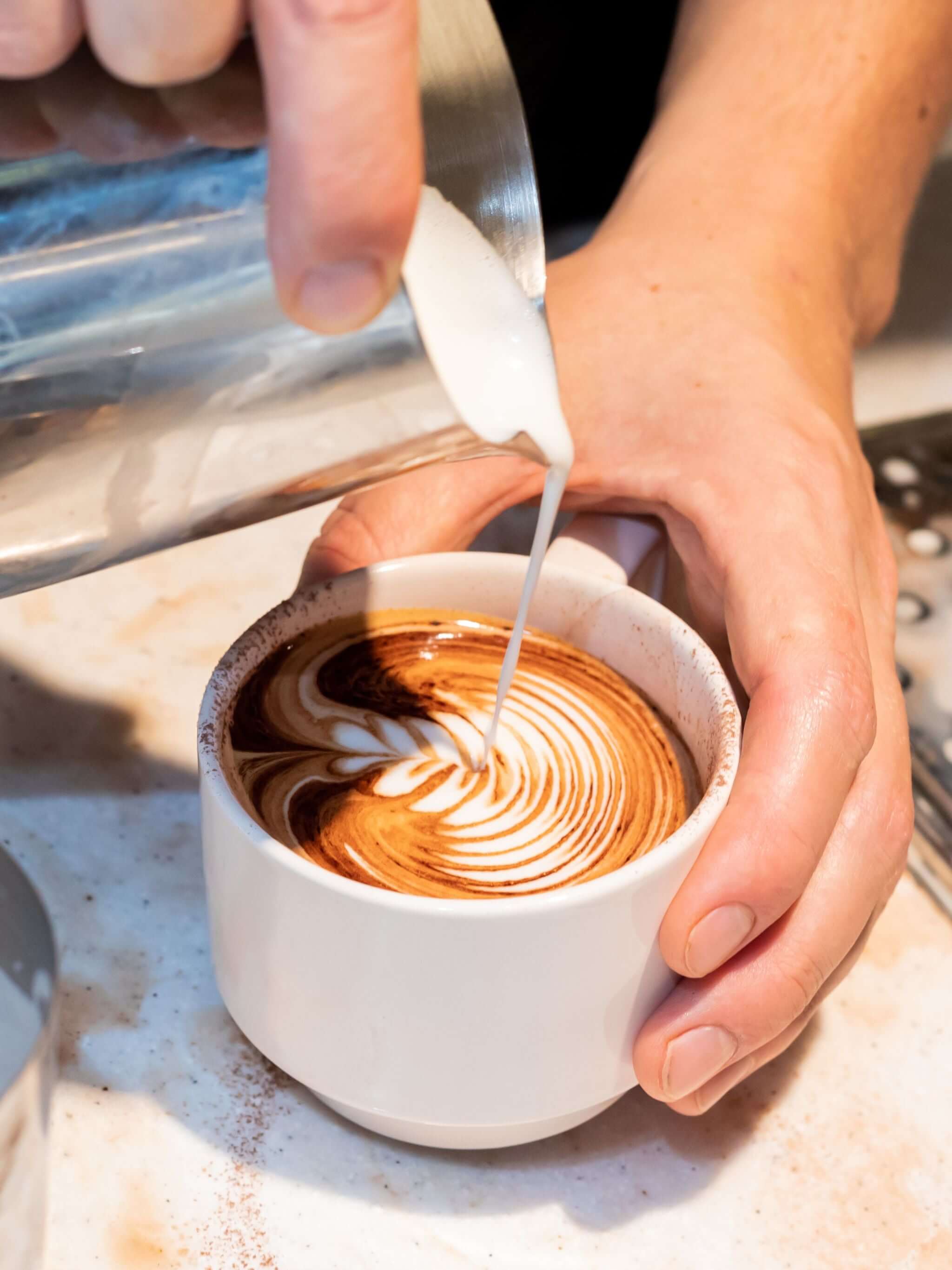 Latte art pour into branded coffee mug